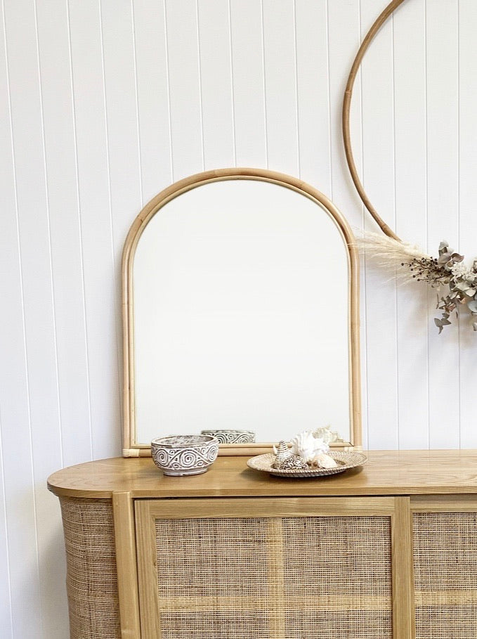 Asha Rattan Arched Mirror lent on top of the Florence Rattan Buffet and displayed with a few costal elements.
