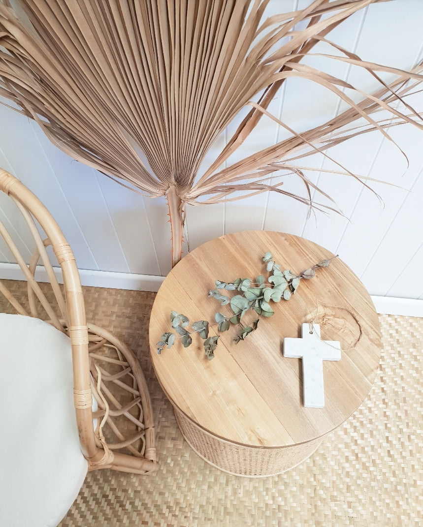 Ava rattan and timber side table from birds-eye view styled with trinkets and next to a rattan chair. 