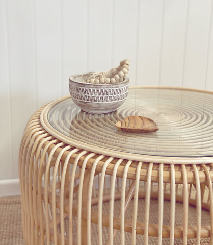 Bessie rattan coffee table with glass top styles with costal bowl and beads.