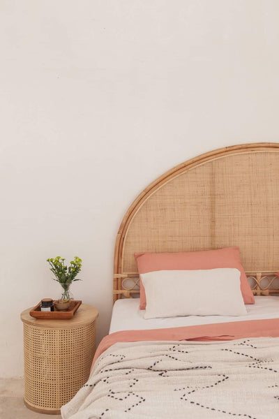 Koko Collective's Arched Natural Rattan Bedhead, displayed in a bedroom with the Ava bedside table, linen bedding and other natural styling details.