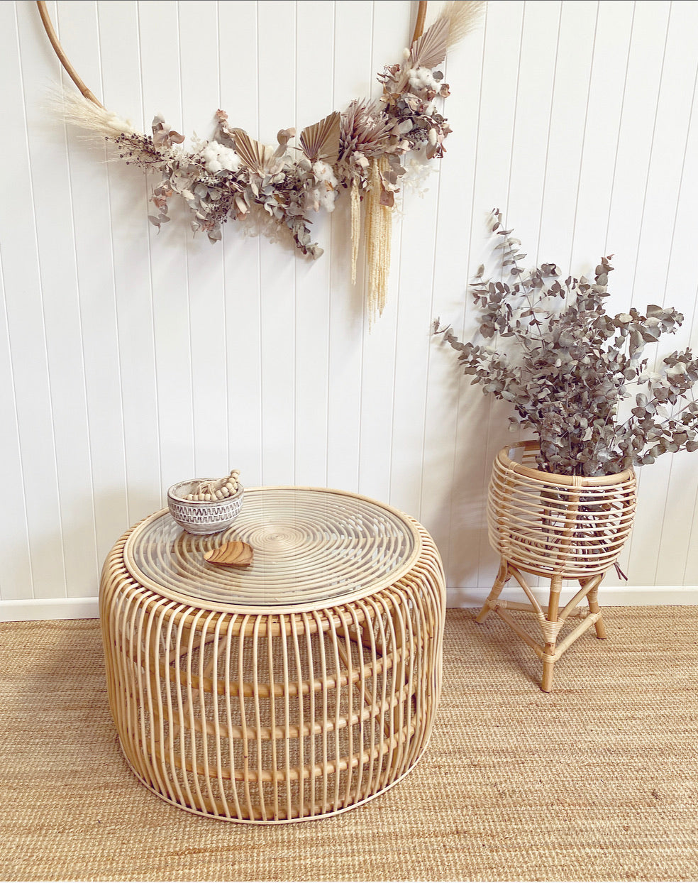 Bessie rattan coffee table with glass top styles with costal bowl and beads.