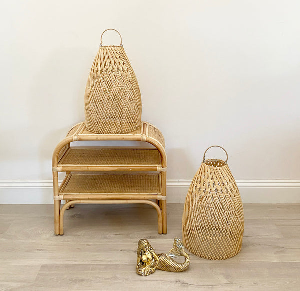 2 Ava rattan pendent light shades positioned on the ground and on top of the Jake bedside and one on the ground. 