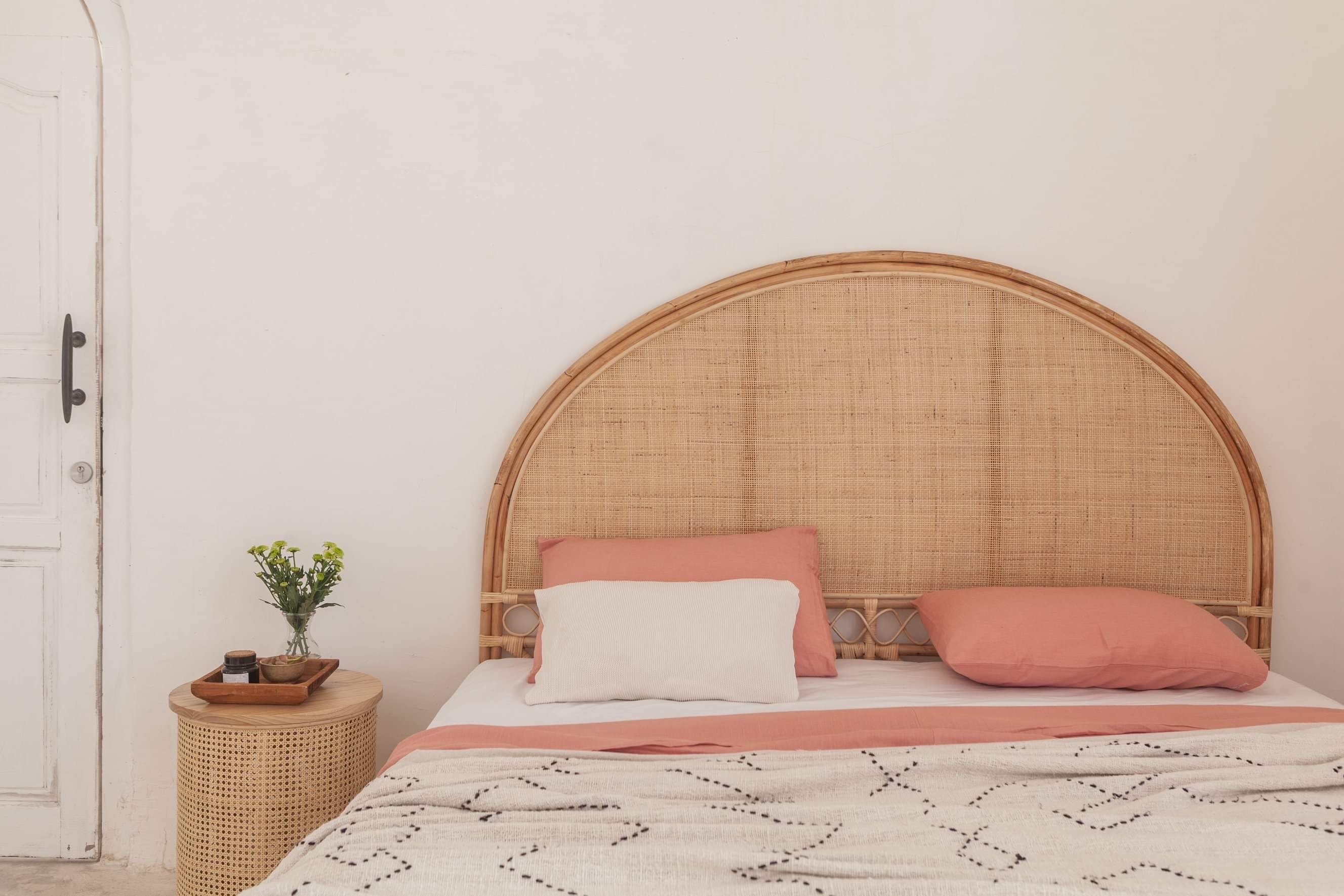 Koko Collective's Arched Natural Rattan Bedhead, displayed in a bedroom with the Ava bedside table, linen bedding and other natural styling details.